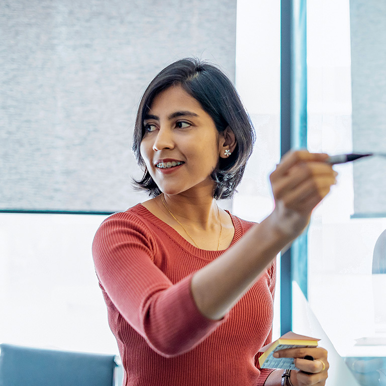 A young professional woman pointing at a visual presentation in a bright office, engaged in a strategic discussion.