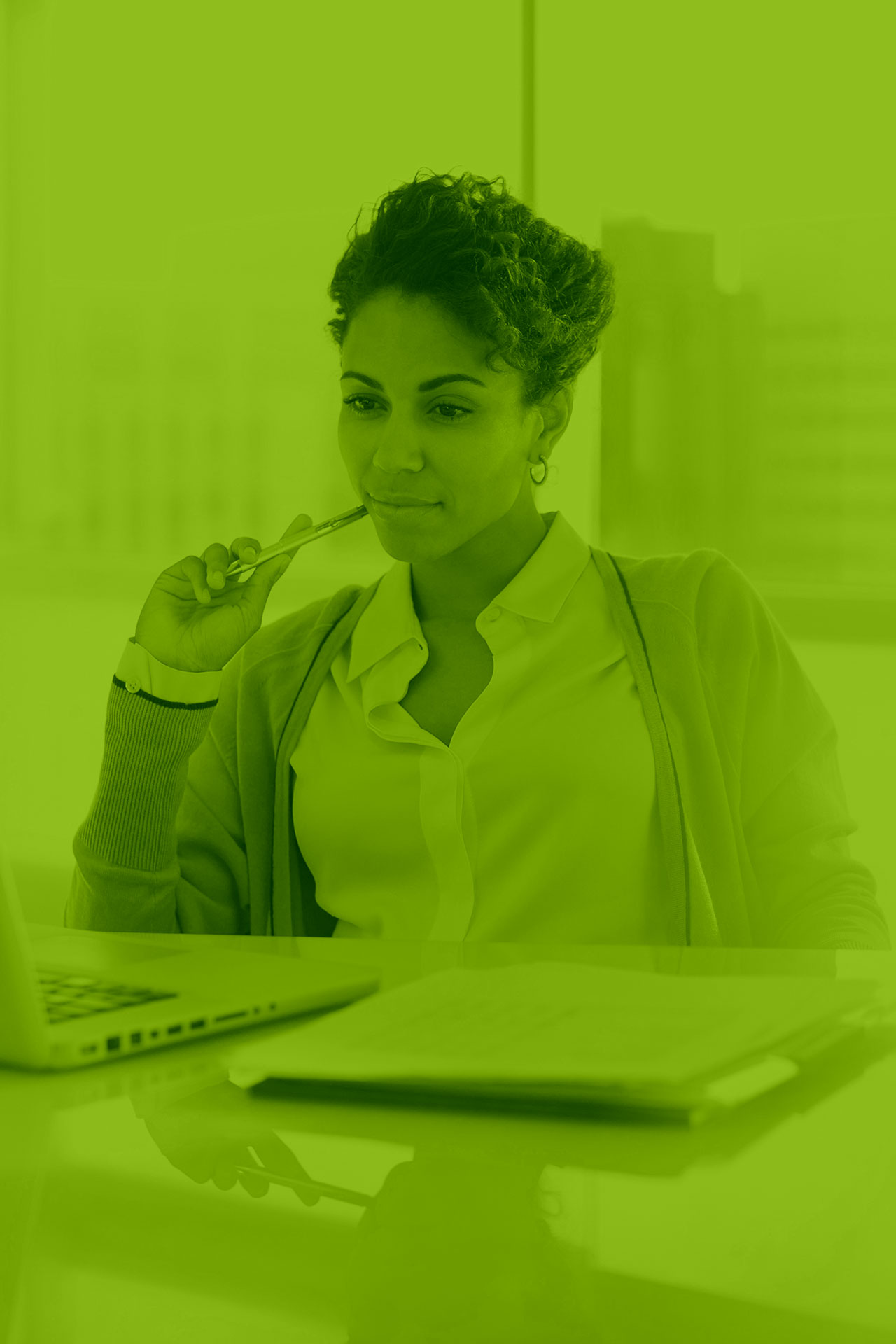 Professional woman at her desk in an office setting, pondering over SEO strategies with her computer and notes.